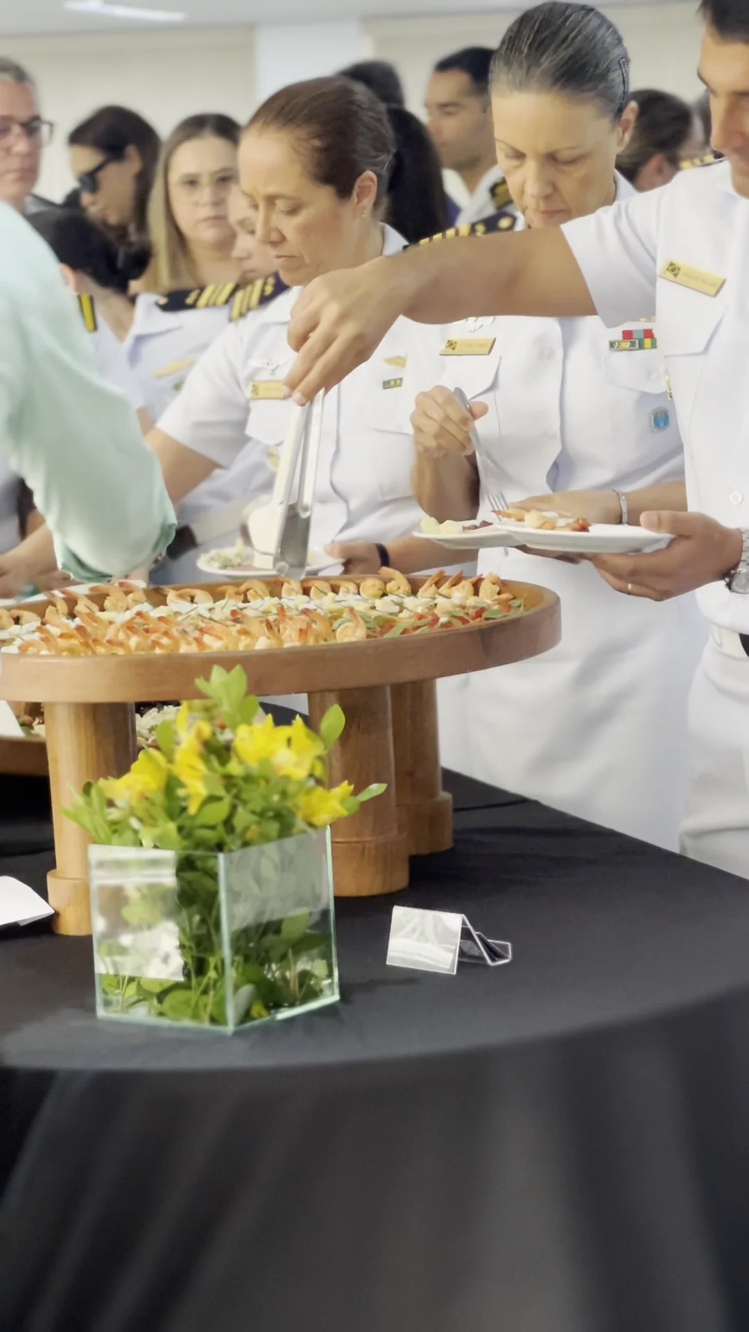 Oficiais da Marinha do Brasil servem-se na mesa principal de canapés e salgados durante o evento.