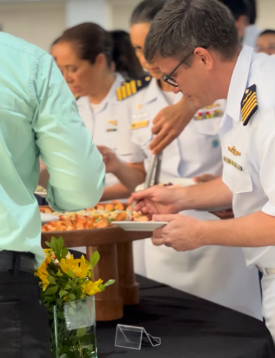 Oficial da Marinha serve-se na mesa do coffee break ao lado de outros convidados militares.