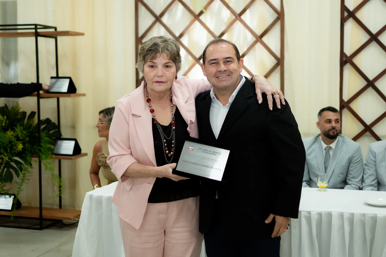 Duas participantes posam com uma placa de homenagem durante a cerimônia
